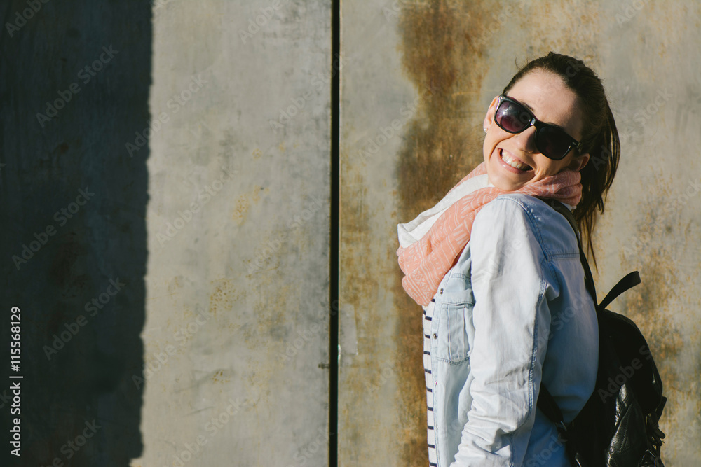 Obraz premium Urban portrait of woman wearing sunglasses, smiling at the camer