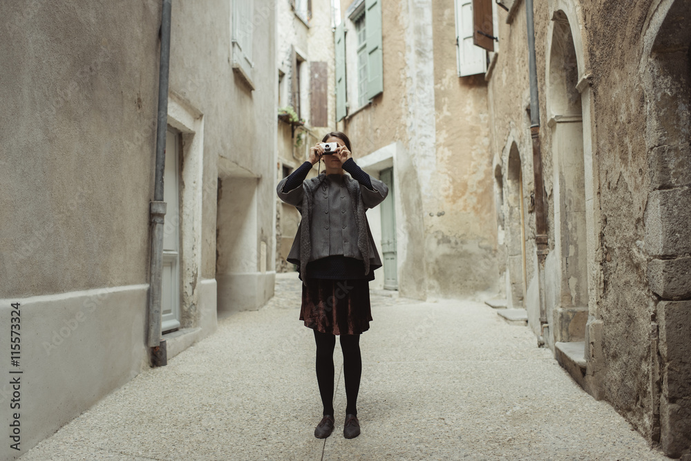 Young woman taking photo with camera in old town