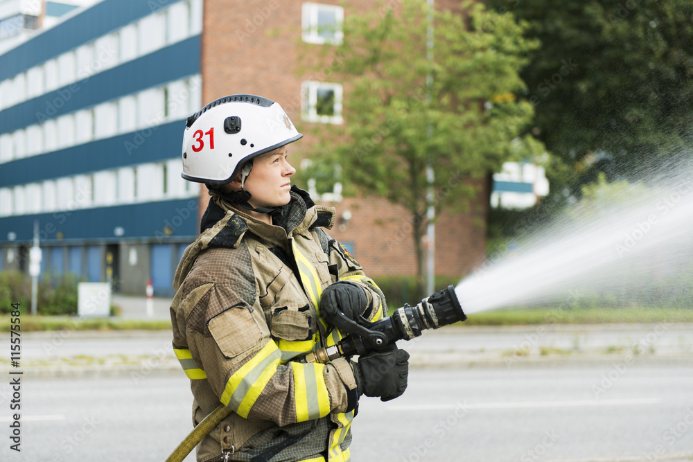 Firefighter using fire hose in street Firefighter using fire hose in street