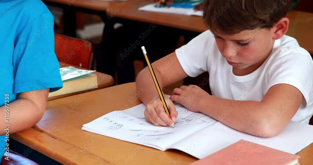 Little boy drawing in notepad in classroom 