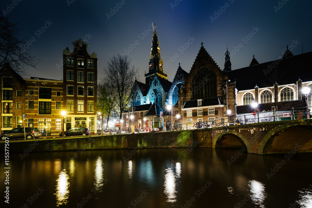 The Oude Church and a canal at night, in Amsterdam, The Netherla