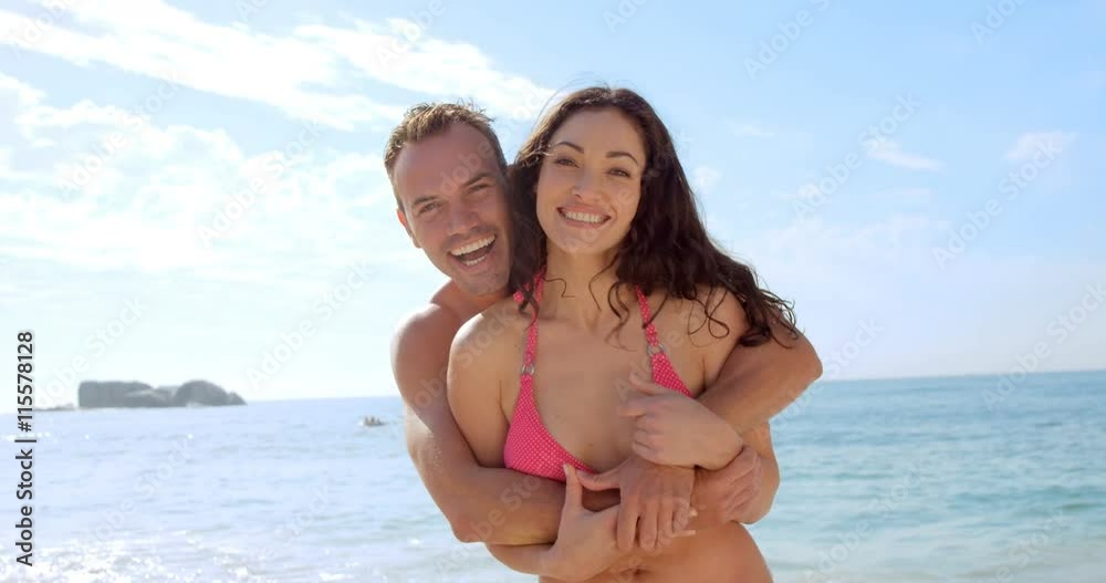 Happy couple smiling at camera on the beach Happy couple smiling at camera on the beach