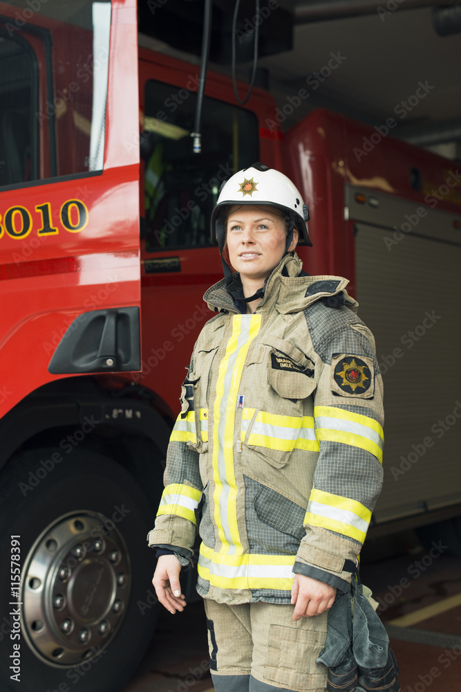 Sweden, Smiling female firefighter by fire engine Sweden, Smiling female firefighter by fire engine