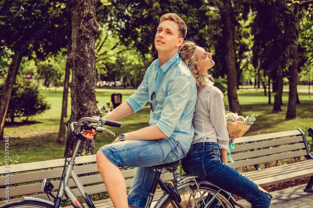 Joyfull couple posing on one bicycle. Joyfull couple posing on one bicycle.