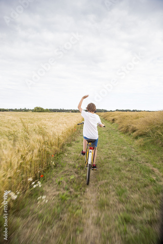 Sweden, Skane, Soderslatt, Beddinge, Boy (12-13) riding bike in wheat field photo