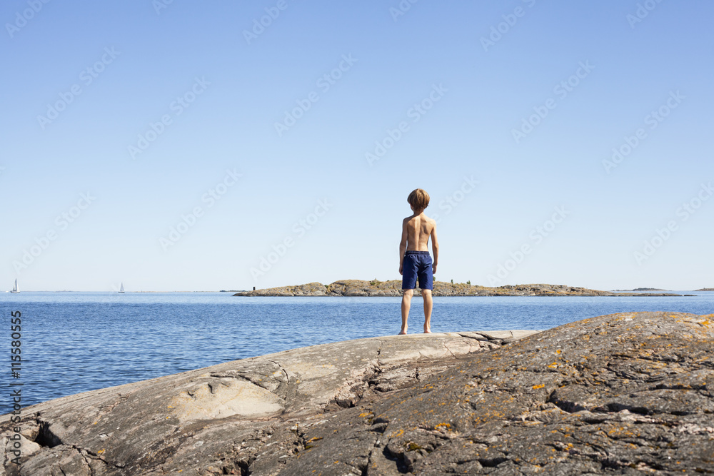 Sweden, Uppland, Runmaro, Barrskar, Rear view of boy (6-7) looking at sea