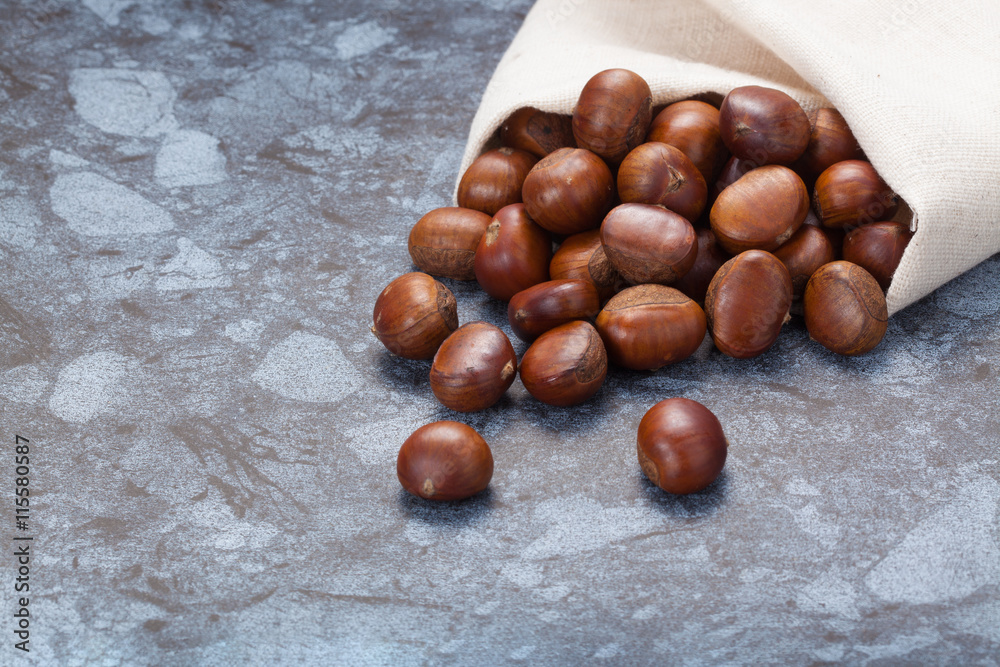 Obraz premium Horizontal image of a pile of chestnuts on stone texture floor with copy space