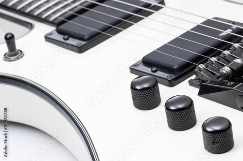 White electric guitar close up of knobs and pickups