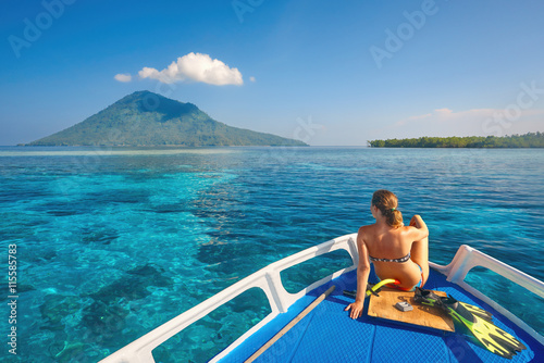 Young woman in swimsuit sit on boat at sunny day looking to a cl