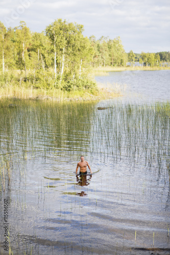 Sweden, Gastrikland, Ockelbo, Man standing in Lake Ekaren photo