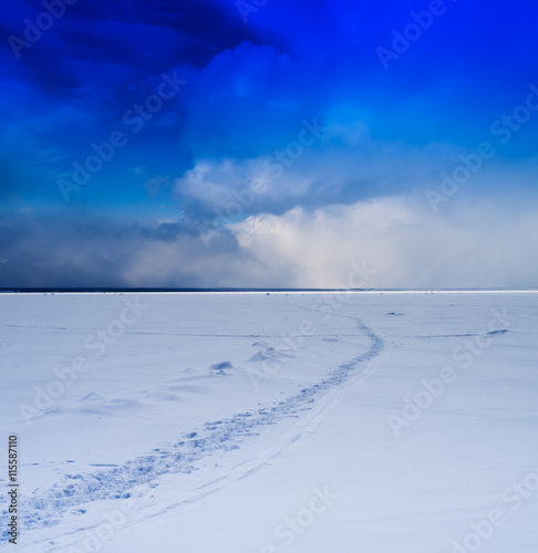 Square vivid winter morning on frozen lake footprints path cloud