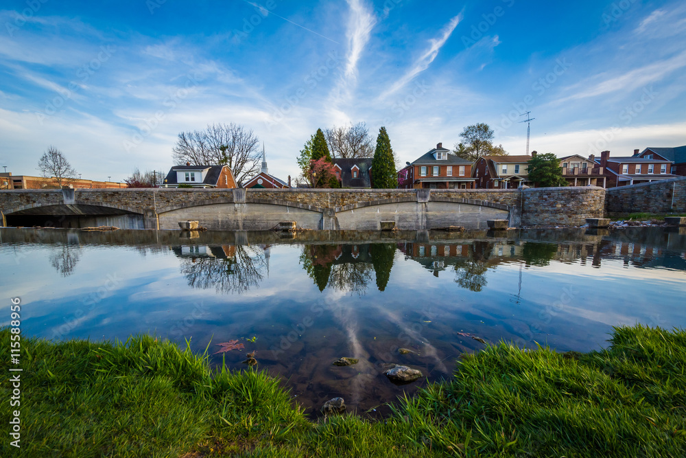 Bridge and houses reflection in Carroll Creek, in Frederick, Mar
