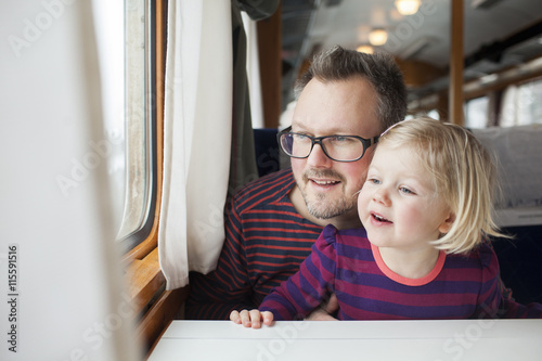 Father and daughter looking through window while traveling by train