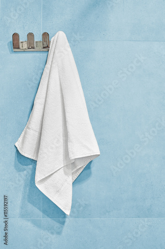 White towel hanging on a wall in bathroom.