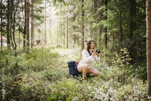 Sweden, Vasterbotten, Norrmjole, Young woman making picture with camera in forest