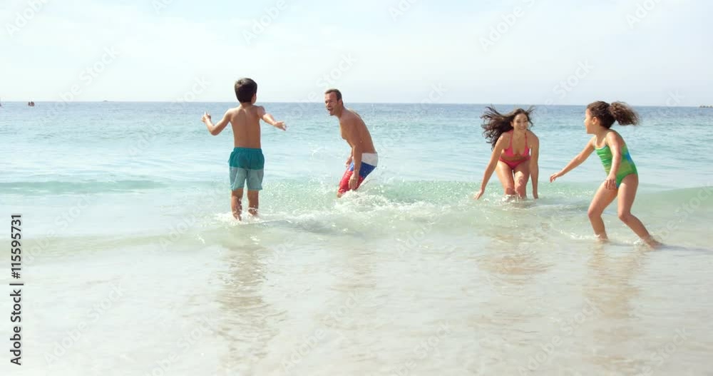 Happy family playing with waves on the beach Happy family playing with waves on the beach
