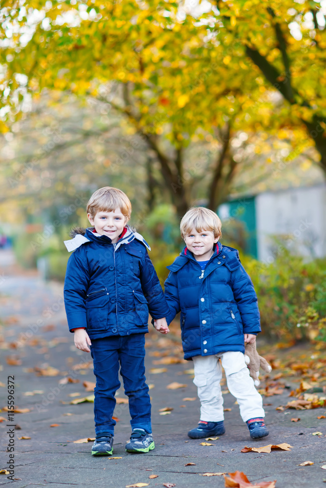 two kid boys walking together in autumn park two kid boys walking together in autumn park