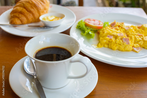 black coffee with  croissant and scrambled eggs.
