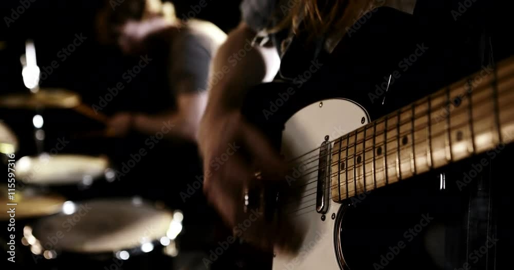 Guitarist and drummer performing together on black screen