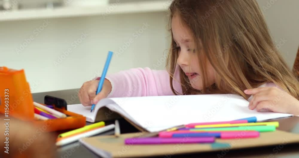 Little girl drawing at the kitchen table and smiling at camera
