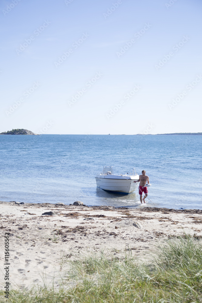 Sweden, Swedish West Coast, Halland, Kungsbackafjorden, Man pulling yacht on beach Sweden, Swedish West Coast, Halland, Kungsbackafjorden, Man pulling yacht on beach