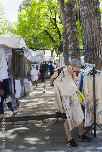 France, Alpes-Maritimes, Tourrettes sur Loup, Place de la Libération, Woman trying on dress at flea market photo