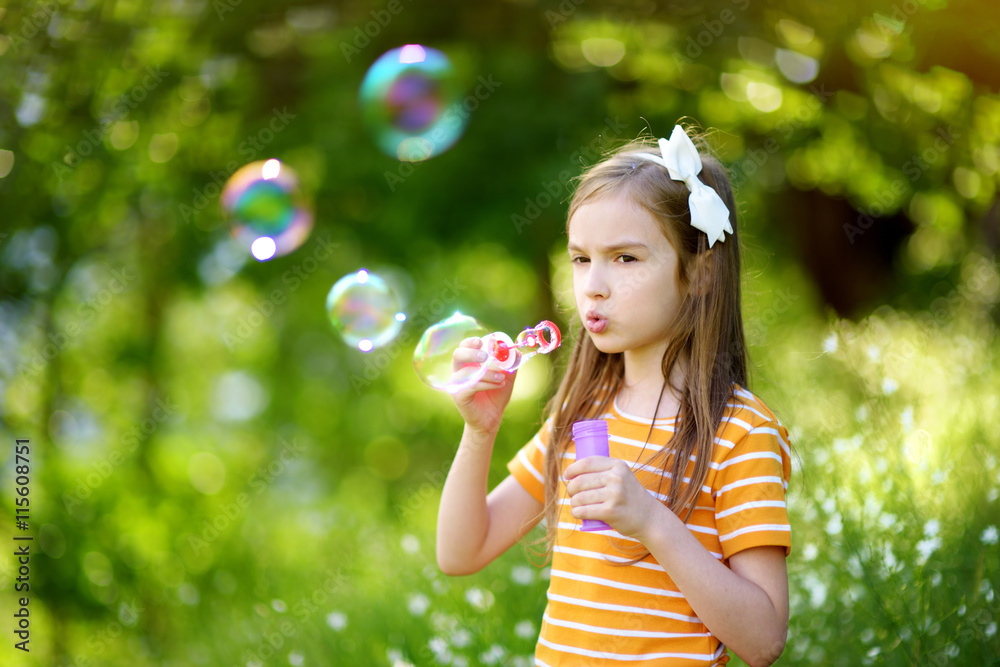 Funny lovely little girl blowing soap bubbles on a sunset outdors