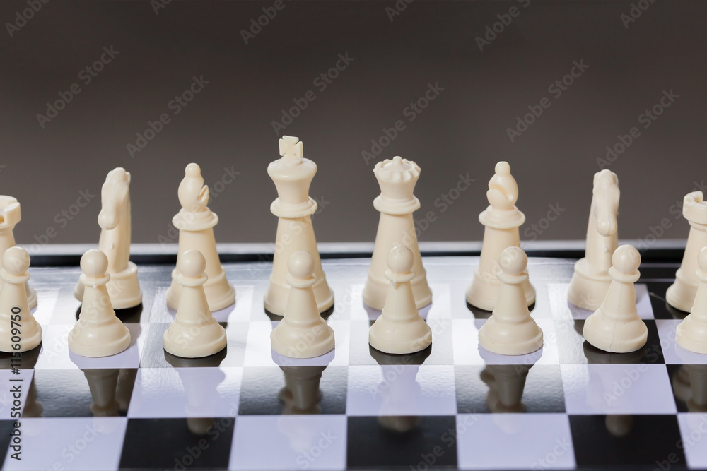 Chess pieces lining up on Chess board on dark background behind Chess pieces lining up on Chess board on dark background behind