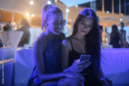 Girls checking a text message on a smart phone photo