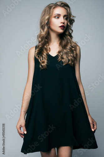 beautiful girl in a black dress looking to the side on a gray background. fashion photography