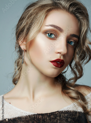 a large portrait of a very beautiful girl. girl with a professional make-up and a professional hair styling. girl with red lips  big eyes on a gray background.