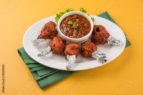 chicken lolipop, chicken winglet, tandoori chicken. Famous indian non veg dish, roasted chicken covered with silver foil, served with spicy chutney, indian chinese appetizer photo