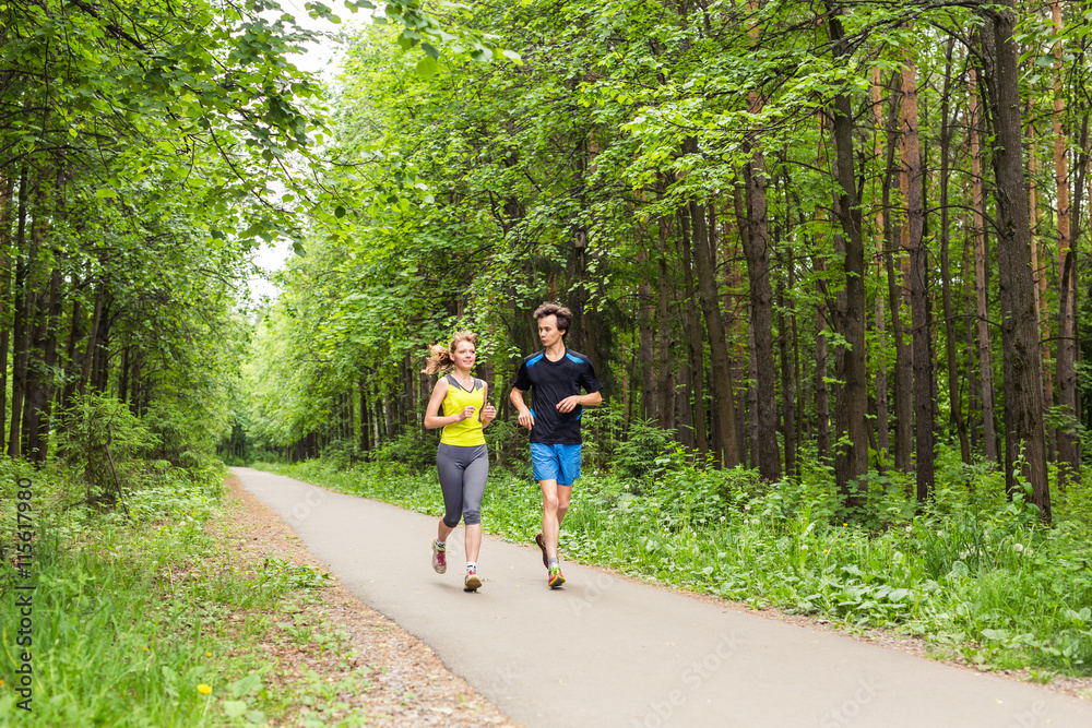 Fototapeta premium Young Couple Running In Wooded Forest Area - Fitness Healthy Lifestyle Concept