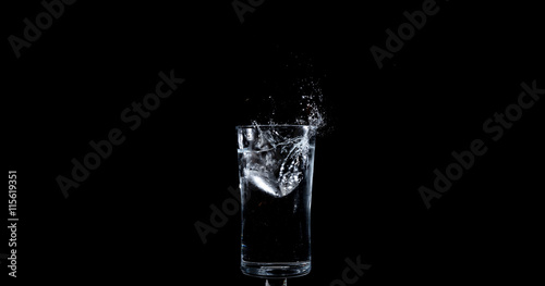 Ice landing in glass of water making a splash