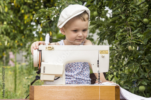 boy at the sewing machine sews in nature