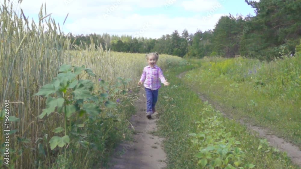 Little girl running on a rural road near the wheat field and smiling. toward the camera . Wide shot.Slow motion. Little girl running on a rural road near the wheat field and smiling. toward the camera . Wide shot.Slow motion.