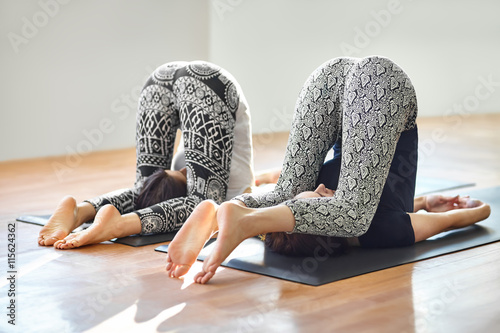 Two young women doing yoga asana easy plow pose photo