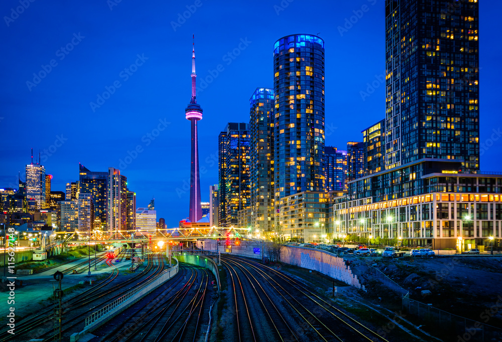 View of a rail yard and modern buildings in downtown at night, f - obrazy, fototapety, plakaty 