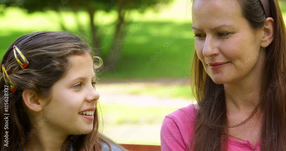 Mother and daughter chatting on a park bench Mother and daughter chatting on a park bench