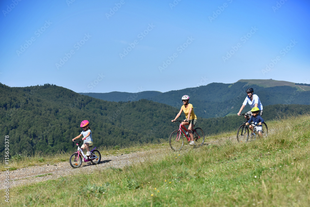 Parents with kids riding bikes in moutain path