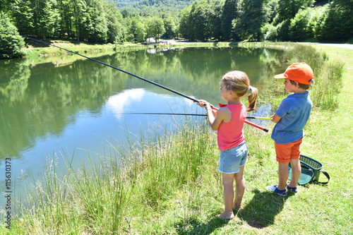 Kids fishing by mountain lake in summer