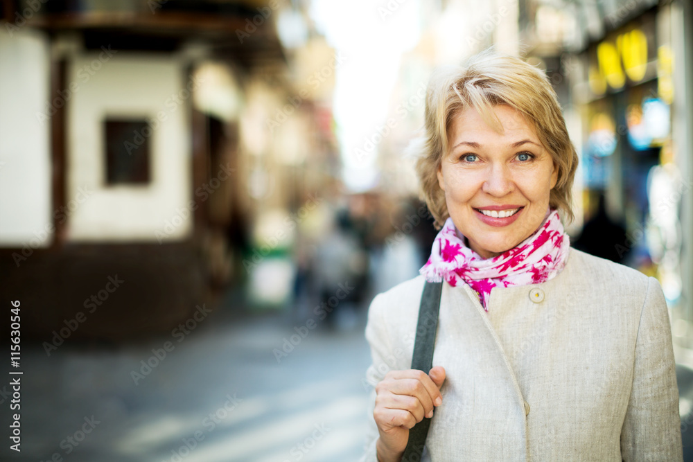 Cheerful retiree woman having a walk in city