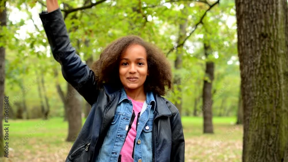 young african charming surprised girl jumps and raises arms up to the sky in the park - satisfied - eye contact young african charming surprised girl jumps and raises arms up to the sky in the park - satisfied - eye contact