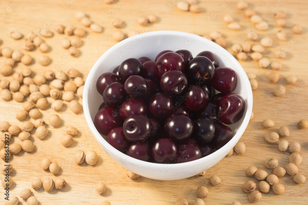 Berries of ripe cherry on a white plate on a background of wooden boards and cherry seed Berries of ripe cherry on a white plate on a background of wooden boards and cherry seed