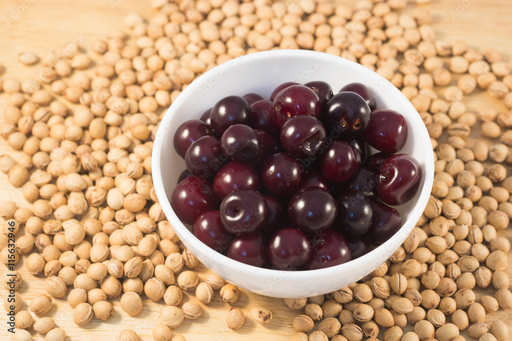 Berries of ripe cherry on a white plate on a background of wooden boards and cherry seed Berries of ripe cherry on a white plate on a background of wooden boards and cherry seed