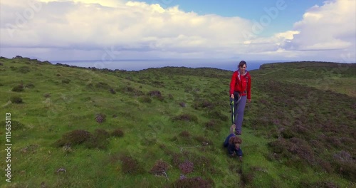 Hiker and their dog walking through heather towards Neist Point with views of Oisgill Bay in the distance on the Isle of Skye, Scotland. UK. photo