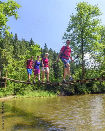 Eine Gruppe Wanderer überquert einen Fluß auf einer Fußgängerbrücke