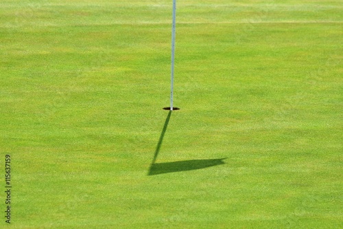 Nice golf course on a sunny summer day. Hole with a flag. Popular outdoor sport.