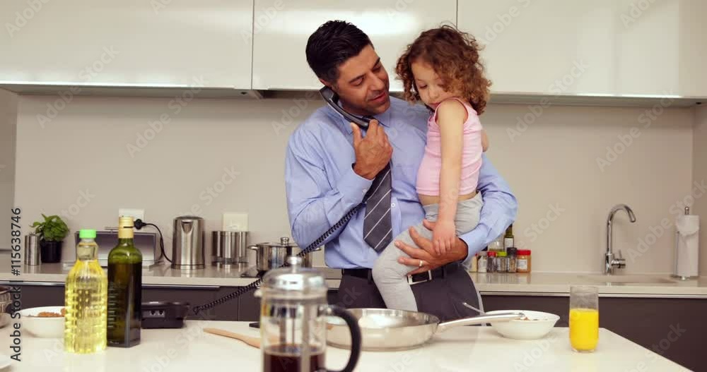 Smiling father holding his young daughter talking on the phone Smiling father holding his young daughter talking on the phone