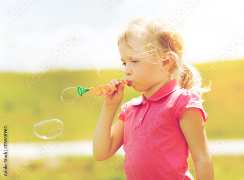little girl blowing soap bubbles outdoors